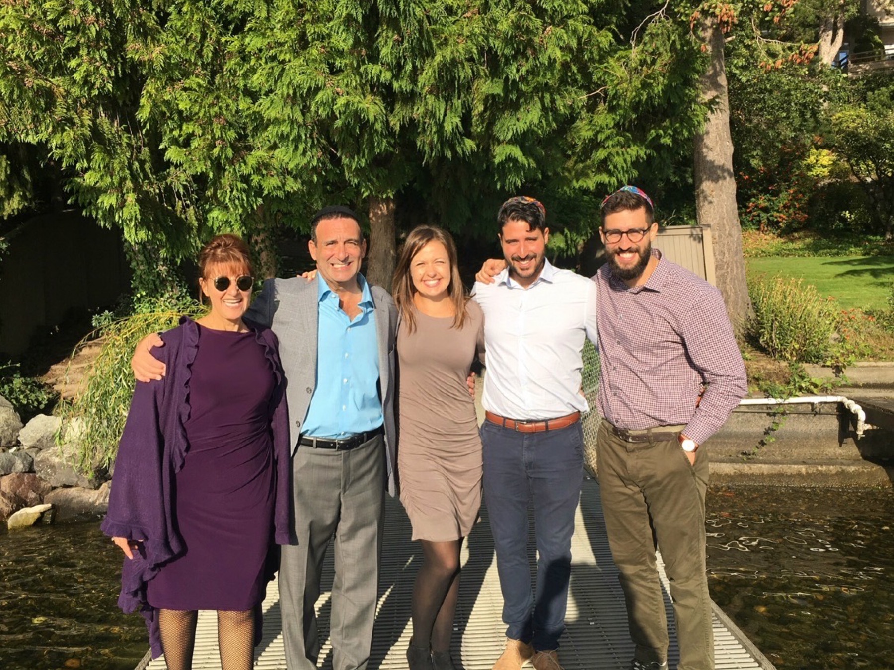 Alan standing with family on a sunny footbridge
