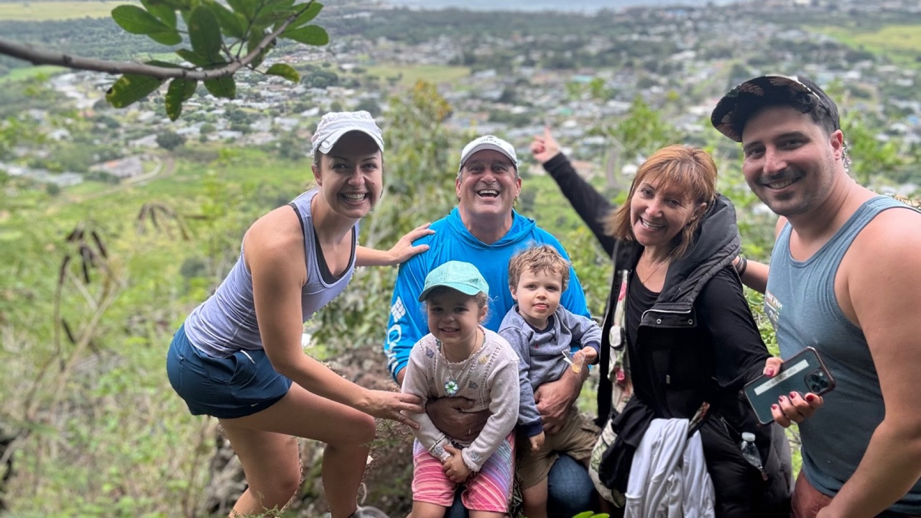 Alan hiking with family and two children above a green valley