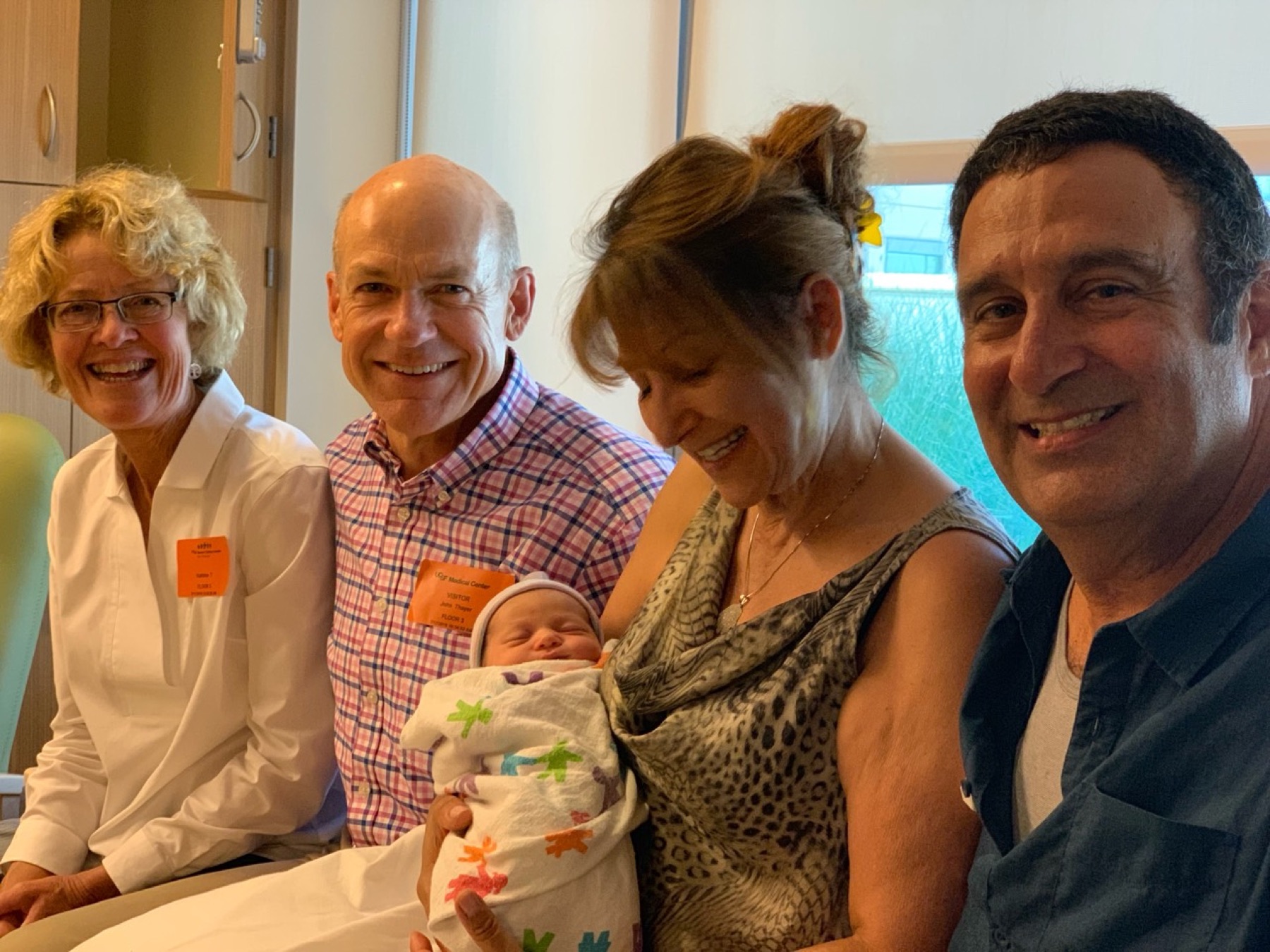Alan smiling beside family welcoming a newborn baby